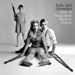 The image is of the album cover for Belle and Sebastian - Girls in Peacetime Want to Dance. The cover is a black-and-white photograph featuring three people in a somewhat staged, dramatic pose. A woman sits in the foreground with leg braces and crutches, flanked by a man sitting next to her. In the background, another woman stands holding a rifle. The composition is in a monochrome palette. The album title, "Girls in Peacetime Want to Dance," is written in a simple, elegant font in the upper right corner, next to the band's name.