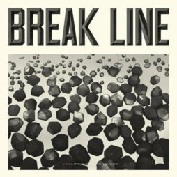 The image features the text "BREAK LINE" in bold, capital letters at the top. Below this, a field of various three-dimensional, geometric, rock-like shapes is scattered across the space. The shapes appear to be randomly placed and have a somewhat metallic or stone-like texture. The overall design is monochromatic, using shades of gray to create a stark, dramatic effect. At the bottom, there is small text that reads, "A Musical by...," giving the impression of a theatrical or musical production.