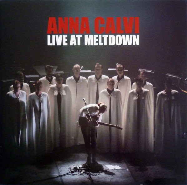 This image is the album cover for "Anna Calvi" in bold red and "Live at Meltdown" in white. The cover features a photo of Anna Calvi performing on stage with a group of people dressed in cloaks.