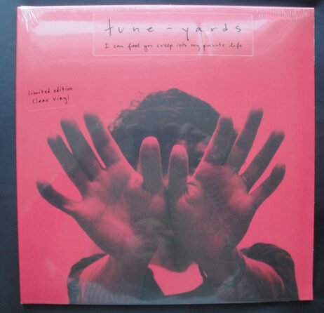 The image features a red-toned photograph of a person with hands splayed out in front of their face, creating a sense of obscurity and motion. The album title and artist's name at the top are handwritten.