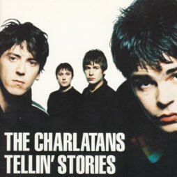The image of the album cover for The Charlatans - Tellin' Stories. The cover features a photograph of the band members, with each of them looking directly at the camera, arranged in a way that creates depth. The colors are slightly muted. The band's name, "The Charlatans," and the album title, "Tellin' Stories," are written in bold, white font at the bottom, standing out against the darker tones of the image.