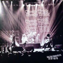 The image you uploaded is the cover for Cheap Trick's "Are You Ready?" which features a live concert scene from December 31, 1979. The black-and-white photograph captures the band performing on stage with dramatic lighting beams extending outwards. The band name "Cheap Trick" is repeated several times in large, glowing font in the background. The image focuses on the members engaged in their instruments.