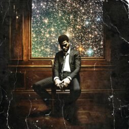 The album cover shows a man dressed in a black suit and tie, seated on a wooden chair in a dimly lit room. He is looking down with his hands clasped together, conveying a contemplative or solemn mood. Behind him is a large window or frame, revealing a vibrant and colorful view of a starry night sky, filled with sparkling stars and cosmic elements. The overall image has a slightly distressed, vintage look with visible creases and scratches.