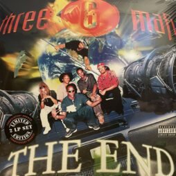 This image is the album cover for "The End" by Three 6 Mafia. The cover features a futuristic design with the group members positioned in the foreground, sitting and standing on what appears to be a metallic structure. In the background, there's a vibrant, space-themed scene with a planet and vivid lights or explosions. The group's name, "Three 6 Mafia," is written at the top in bold red letters, while the album title, "The End," appears at the bottom in large, bold, white text. There is also a sticker on the left side mentioning that this is a limited edition 2 LP set in translucent orange.