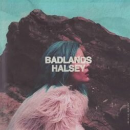The image is the album cover for "Badlands" by Halsey. It features a side profile of Halsey with blue hair, wearing a light-colored fur jacket against a rugged, rocky background. The sky is a muted teal color, contrasting with the dark rocks. The album title "BADLANDS" and artist name "HALSEY" are in bold white text across the center.