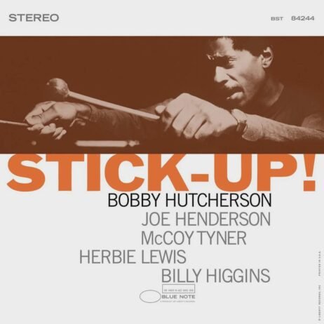 The album cover features a close-up image of Bobby Hutcherson playing the vibraphone in an intense, focused expression. The title "STICK-UP!" is prominently displayed in large, bold orange letters across the center. Below, in smaller black and gray text, the artist's name, Bobby Hutcherson, is followed by the names of the featured musicians: Joe Henderson, McCoy Tyner, Herbie Lewis, and Billy Higgins.