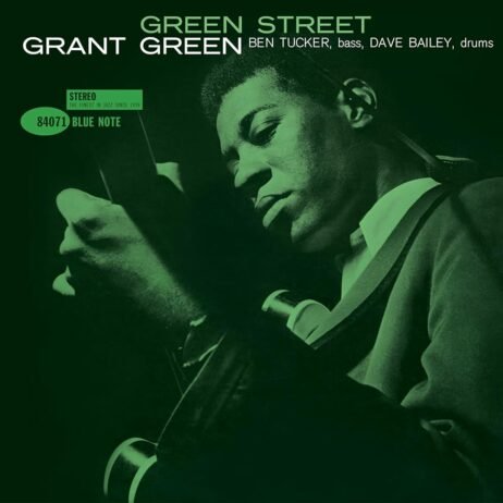 The album cover of Green Street by Grant Green features a green monochromatic image of Grant Green playing his guitar. He has a focused expression. The album title, Green Street, is displayed in bold, white text above his name. The musicians accompanying him, Ben Tucker on bass and Dave Bailey on drums, are listed below his name.