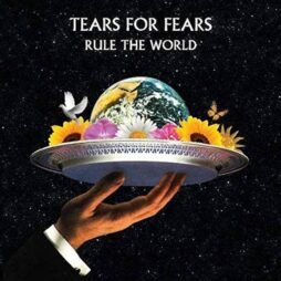 The image is the album cover for "Rule The World" by Tears for Fears. It features a hand holding a silver tray with a miniature Earth surrounded by colorful flowers, including sunflowers, daisies, and other blooms. A white dove and a butterfly hover near the planet, all set against a starry black background. The band's name, "Tears For Fears," and the album title, "Rule The World," are written at the top in bold, white text.