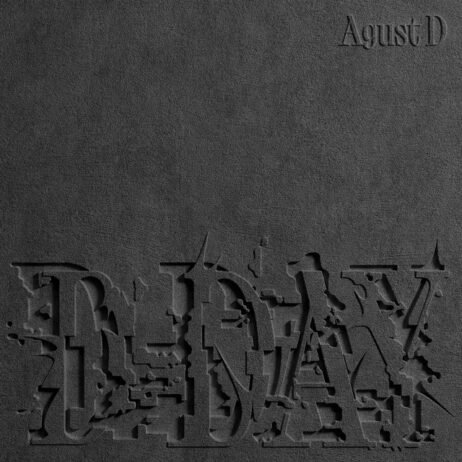 The album cover features a dark, textured background with the title "D-DAY" embossed at the bottom in a distressed and fragmented font. The artist name, "Agust D," is subtly placed in the top right corner in a clean, minimalist font. The monochromatic design, using various shades of black and grey, creates a stark, impactful aesthetic.